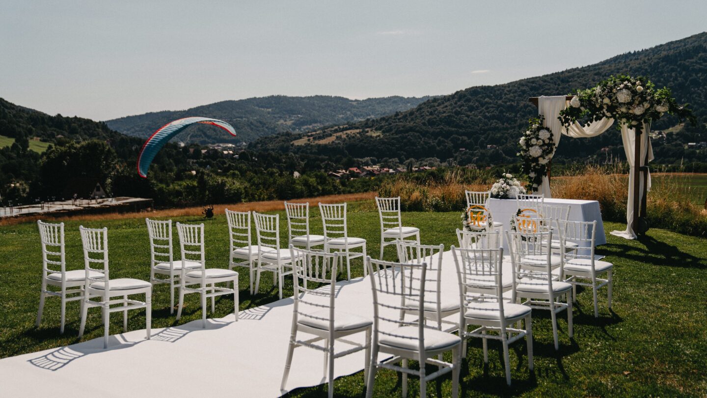 Krzesła przygotowane do ceremonii ślubnej na lotnisku Żar. W tle ląduje paralotnia