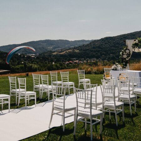 Krzesła przygotowane do ceremonii ślubnej na lotnisku Żar. W tle ląduje paralotnia