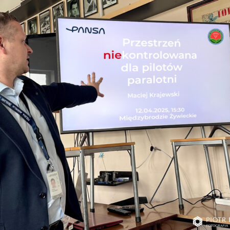 Maciej Krajewski prezentuje tytuł wykładu "Przestrzeń [nie]kontrolowana dla pilotów paralotni"